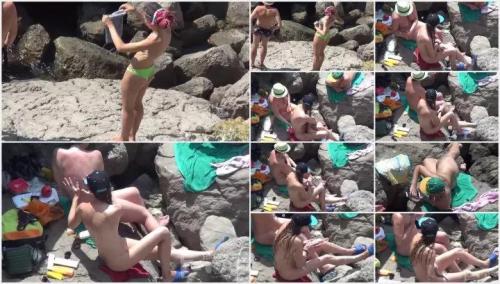 Nudist women crossing rocks to enter water